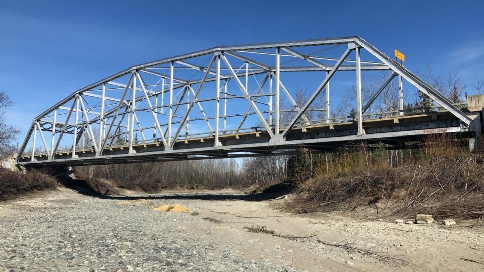 An old silver metal bridge over a dry river bed