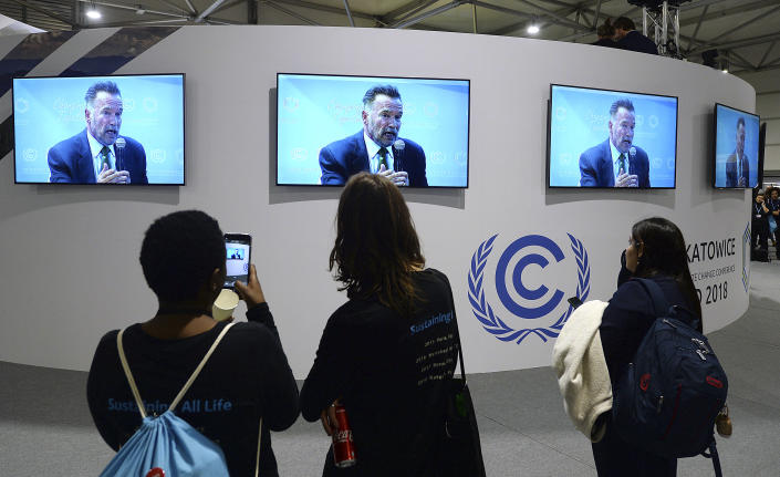 Visitors to the U.N. climate conference watch a speech by Arnold Schwarzenegger, in Katowice, Poland, Monday, Dec. 3, 2018. The COP24 UN Climate Change Conference is taking place in Katowice, Poland. Negotiators from around the world are meeting for talks on curbing climate change. (AP Photo/Czarek Sokolowski)