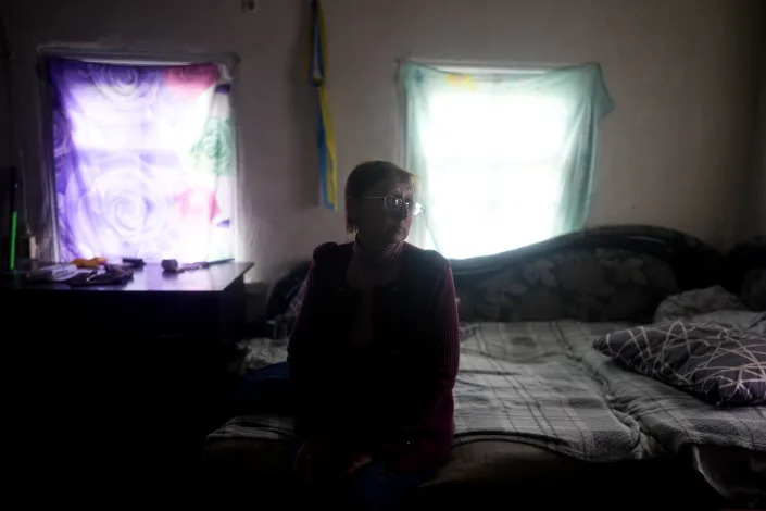 Nila Zelinska sits inside her neighbor's home as she arrives to her town to find out her house was destroyed during attacks in Potashnya, on the outskirts of Kyiv, Ukraine, Tuesday, May 31, 2022. (AP Photo/Natacha Pisarenko)