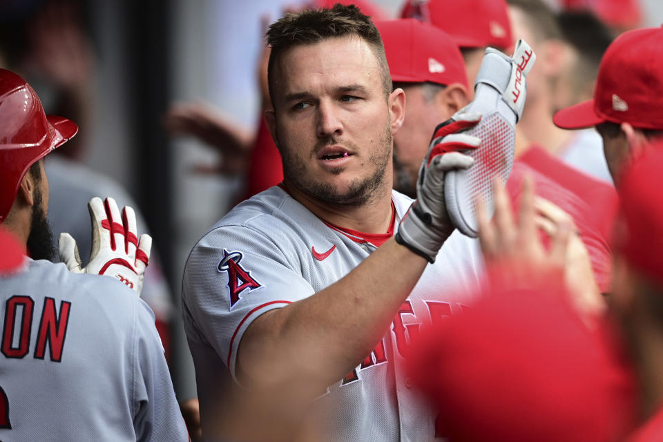 Los Angeles Angels' Mike Trout is congratulated in the dugout after scoring on a sacrifice fly by Anthony Rendon during the third inning of the team's baseball game against the Cleveland Guardians, Saturday, May 13, 2023, in Cleveland. (AP Photo/David Dermer)