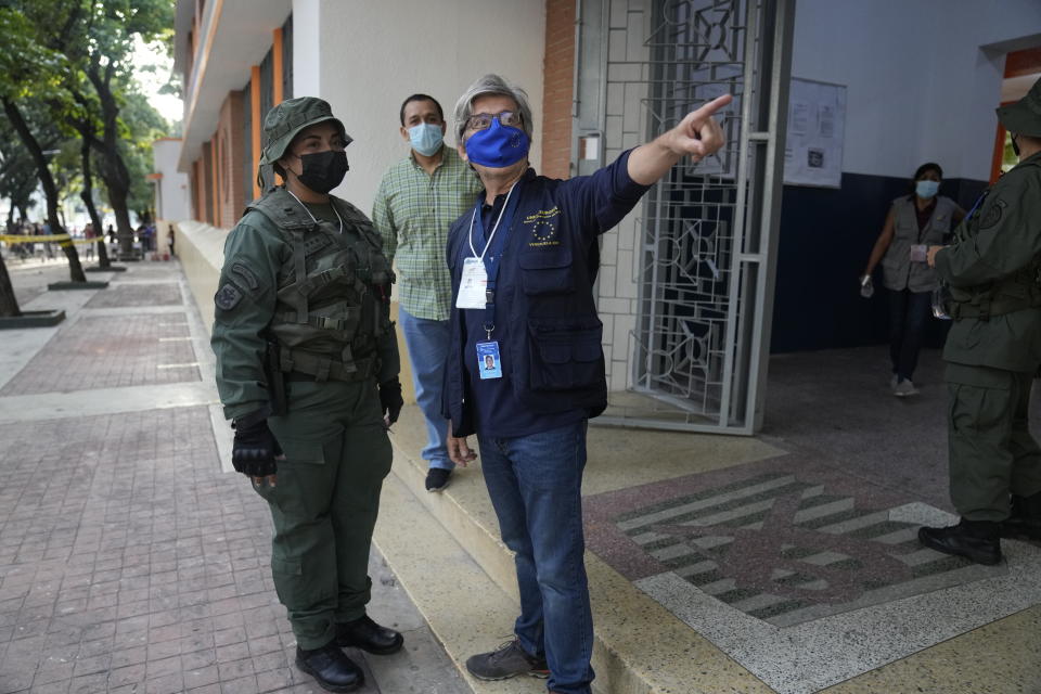 A European Union observer points out a detail to a soldier during regional elections, at a polling station in the Andres Bello school in Caracas, Venezuela, Sunday, Nov. 21, 2021. Venezuelans go to the polls to elect state governors and other local officials. (AP Photo/Ariana Cubillos)
