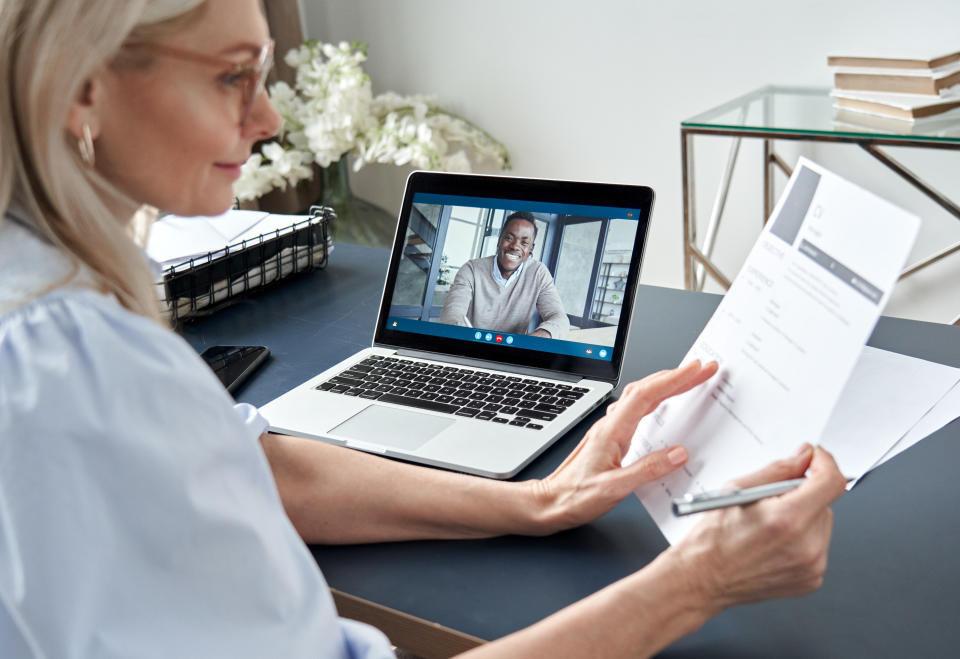 Woman looks at a resume while talking to a candidate on the computer