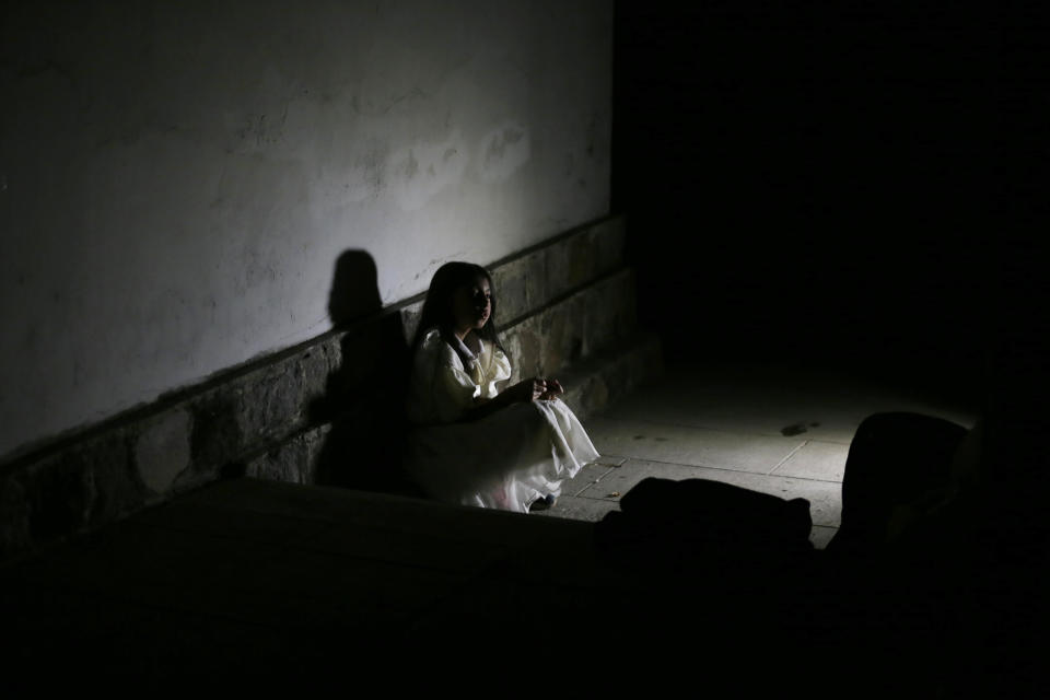 Susi who one of the performers waits for tourist at El Tejar cemetery in Quito, Ecuador, Wednesday, Sept. 11, 2019. In many cities across the globe, tourism groups have begun encouraging visitors to take a step toward the dark side as an opportunity to reflect on the past and the very nature of humanity. (AP Photo/Dolores Ochoa)