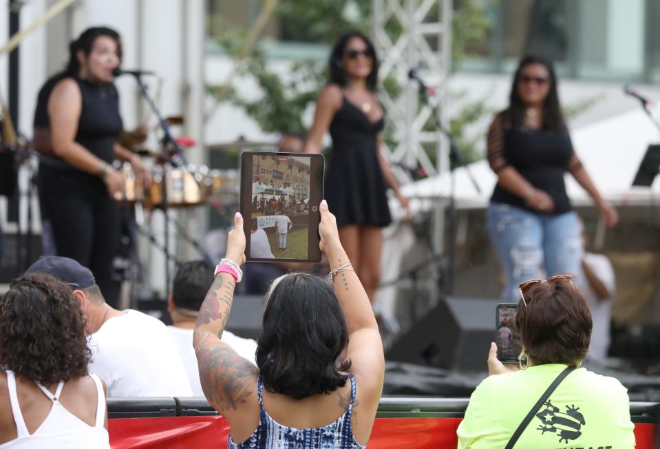 Los asistentes al festival sostienen dispositivos para grabar la música en vivo de Sonidos Unidos durante el último día del Festival Puertorriqueño 2021 en Parcel 5 en el centro de Rochester.