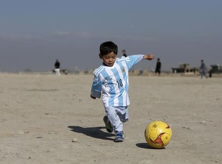 Five year-old Murtaza Ahmadi, an Afghan Lionel Messi fan, wears a shirt signed by Barcelona star Lionel Messi as he plays football at the open area in Kabul, Afghanistan February 26, 2016. REUTERS/Omar Sobhani