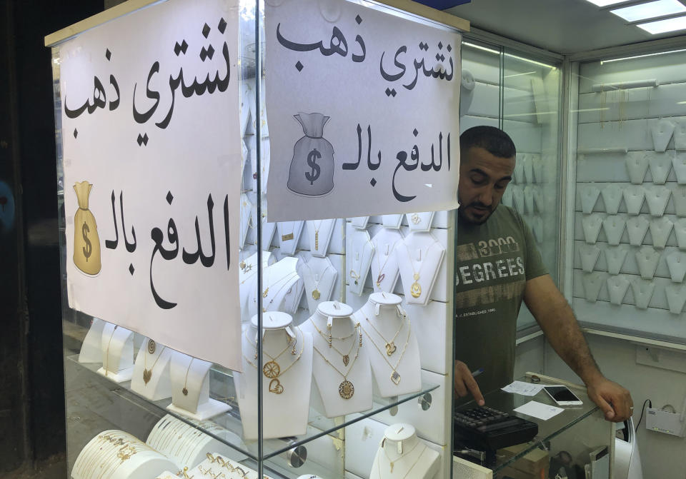 A man works in a jewelry store where an Arabic sign reads, "We buy gold and pay in dollars," in Beirut, Lebanon, Monday, July 6, 2020. Lebanon's financial meltdown has thrown its people into a frantic search for dollars as the local currency's value evaporates. With tens of thousands thrown into poverty, the turmoil is fueling bitterness at banks and politicians. (AP Photo/Hussein Malla)