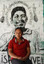 Liliana Velazquez poses for a photo in front of a mural depicting her murdered husband and community activist Samir Flores in Amilcingo, Morelos state, Mexico, Saturday, Feb. 22, 2020. Last year, Flores who had drummed up opposition against a power plant being built in the area was shot dead outside his home in the town of Amilcingo. (AP Photo/Eduardo Verdugo)