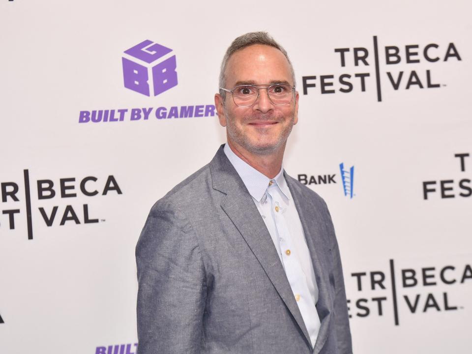 director tim sutton in a grey suit on the tribeca red carpet for taurus, smiling at the camera