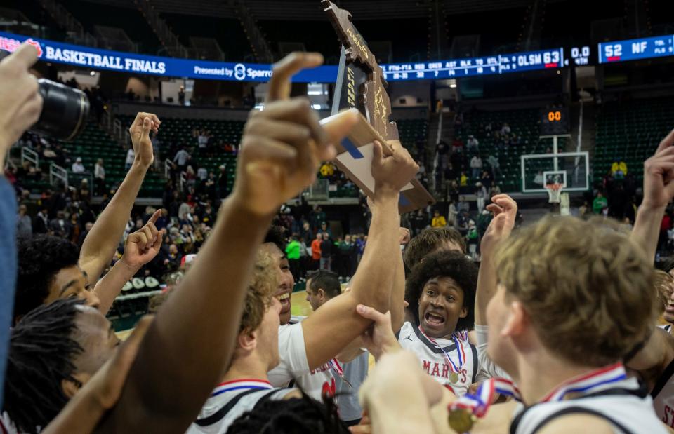Orchard Lake St. Mary's players celebrate with the MHSAA trophy after defeating North Farmington 63-52 during the MHSAA Div. 1 state finals at the Breslin Center in East Lansing on Saturday, March 16, 2024.