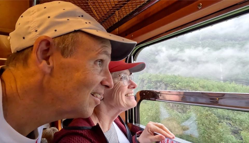 John and Beverly Martin looking out a train window onto a Norwegian forest.