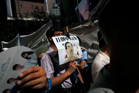 A protester carries a defaced picture of Hong Kong's Chief Executive Leung Chun-ying, during a protest march on the day marking the 19th anniversary of Hong Kong's handover to Chinese sovereignty from British rule, in Hong Kong, China July 1, 2016. The words on poster read "Down the Chinese communists's dog". REUTERS/Tyrone Siu