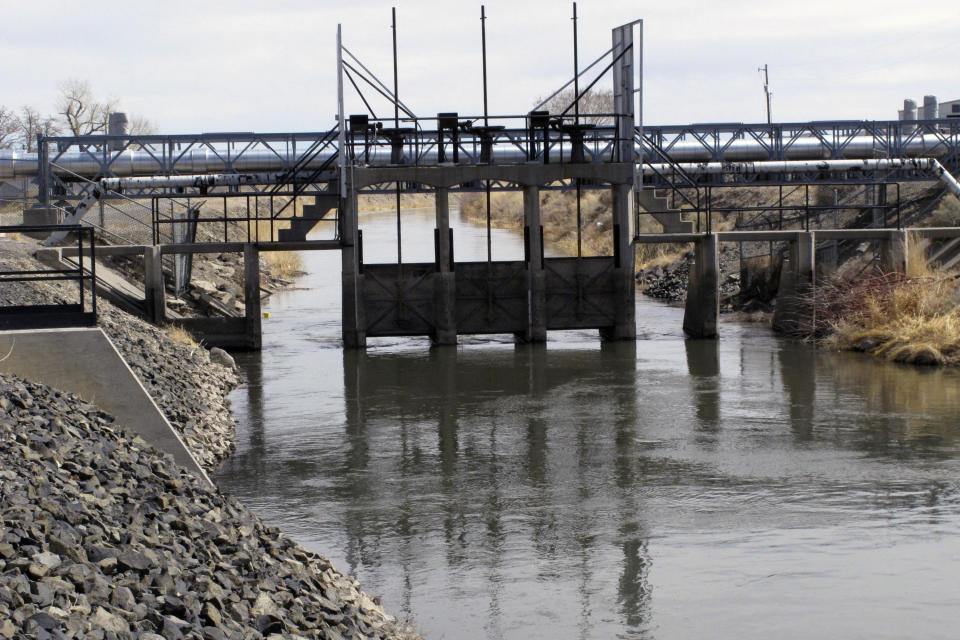 FILE — Water flows through a control gate on an irrigation canal in Fernley, Nev., near Reno on March 18, 2021. A U.S. appeals court has breathed new life into a rural Nevada's town's unusual bid to halt government repairs to an aging, federal irrigation canal that burst and flooded nearly 600 homes 15 years ago. The town of Fernley, area farmers and ranchers in the high desert 30 miles (48 kilometers) east of Reno say the renovation that finally began this year might help guard against another failure of the 118-year-old earthen canal. (AP Photo/Scott Sonner, File)