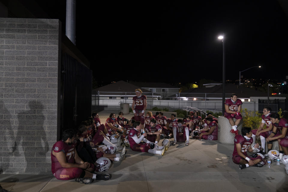 El Modena players rest in an open space due to COVID-19 restrictions during halftime of their high school football game with El Dorado in Orange, Calif., Friday, March 19, 2021. (AP Photo/Jae C. Hong)