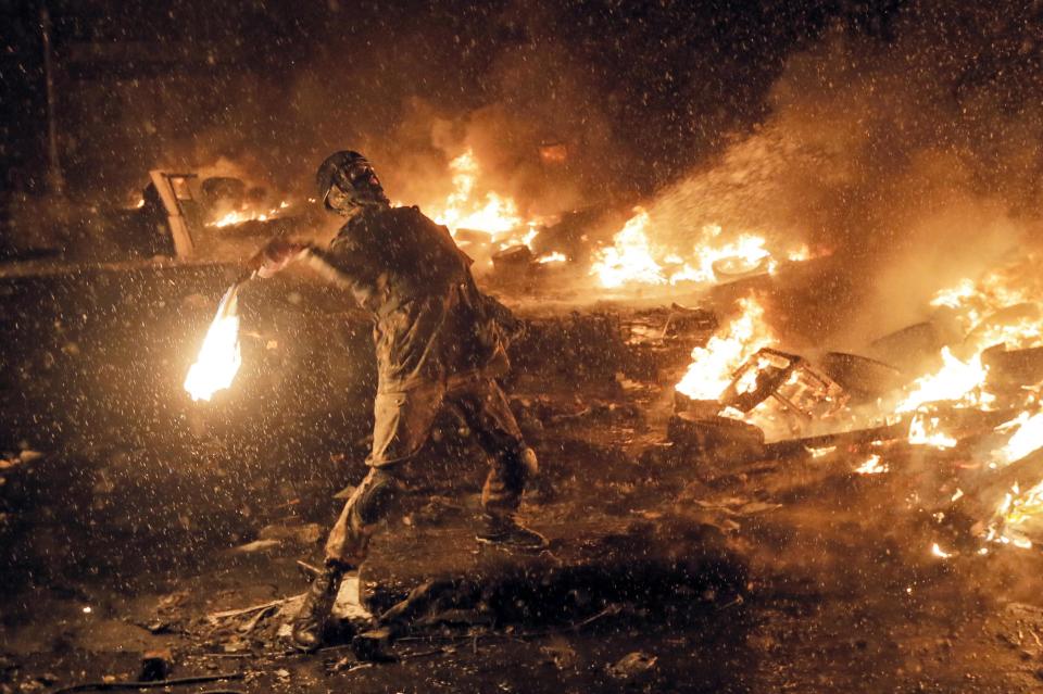 FILE - In this Wednesday, Jan. 22, 2014 file photo a protester throws a Molotov cocktail during clashes with police in central Kiev, Ukraine. After two months of anti-government protests, modern Ukraine has never been so bitterly polarized. To be sure, Ukraine has long been divided. Russia and Europe have vied for dominance for centuries, causing deep cultural differences between the mostly Ukrainian-speaking western and central regions on the one hand, and the Russian-speaking east and south on the other. But as the crisis has deepened, each side has grown stronger in its convictions, and those who stood in the middle have been forced to choose sides. (AP Photo/Efrem Lukatsky, file)