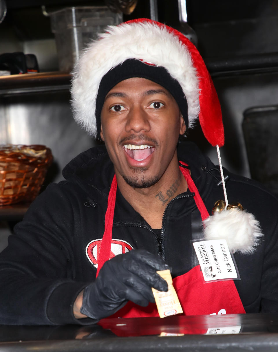 Person in Santa hat serving at an event, smiling, wearing a name badge and black gloves