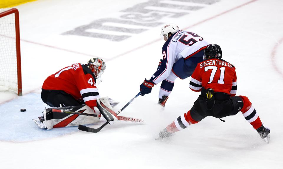 Columbus Blue Jackets right wing Yegor Chinakhov (59) scores a goal against New Jersey Devils goaltender Vitek Vanecek (41) and defenseman Jonas Siegenthaler (71) during the third period of an NHL hockey game Wednesday Dec. 27, 2023, in Newark, N.J. The New Jersey Devils won 4-3 in overtime. (AP Photo/Noah K. Murray)