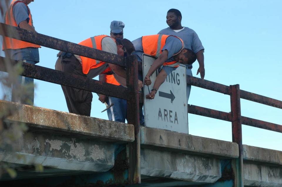 A crew from the Florida Department of Transportation removes fishing signs on the sides of the crumbling Old Seven Mile Bridge in 2008.