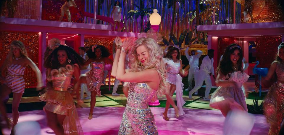 barbie dances with her friends while wearing a disco inspired outfit in a scene from barbie