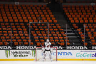 FILE - Arizona Coyotes goaltender Adin Hill guards his net with empty seats behind him during the first period of an NHL hockey game against the Anaheim Ducks in Anaheim, Calif., in this Friday, April 2, 2021, file photo. While the NFL, NBA and Major League Baseball are moving to relax virus protocols when a vast majority of a team’s players, coaches and staff are vaccinated, the NHL finds itself in an uncomfortable position. (AP Photo/Jae C. Hong, File)
