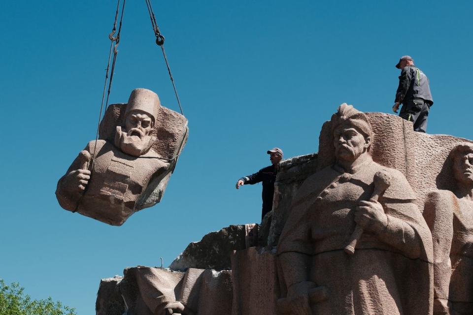 Municipal service workers, under the Arch of Freedom of the Ukrainian People, dismantle a granite monument with a multi-figure group, dedicated to the Pereiaslav Council in Kyiv, Ukraine on April 30, 2024. (Vitalii Nosach/Global Images Ukraine via Getty Images)