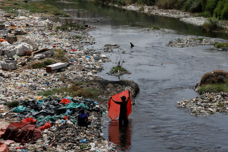 FILE PHOTO: A man washes waste plastic sheets, collected for recycling, in Karachi