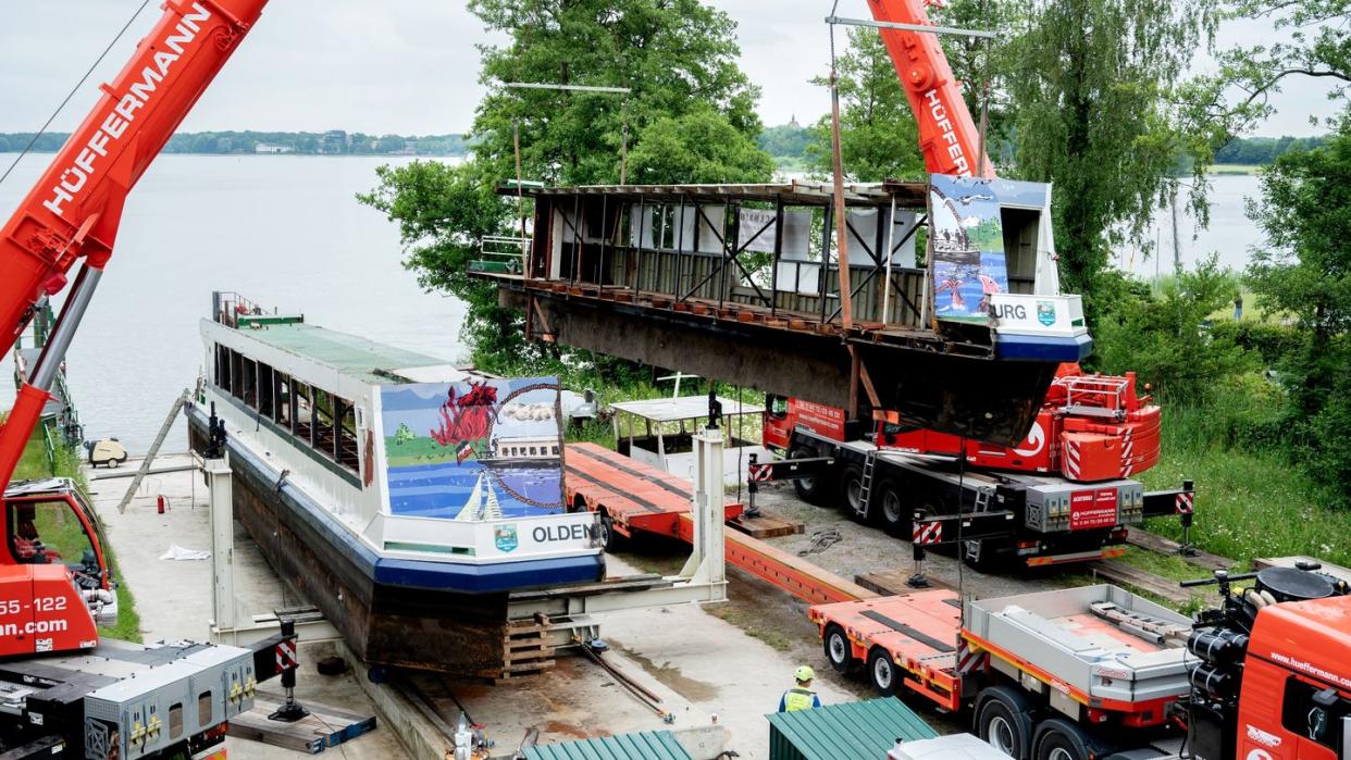 Zwei Mobilkrane heben ein Teilstück des längsseitig zersägten Fahrgastschiffes «MS Oldenburg» am Zwischenahner Meer auf einen Tieflader.