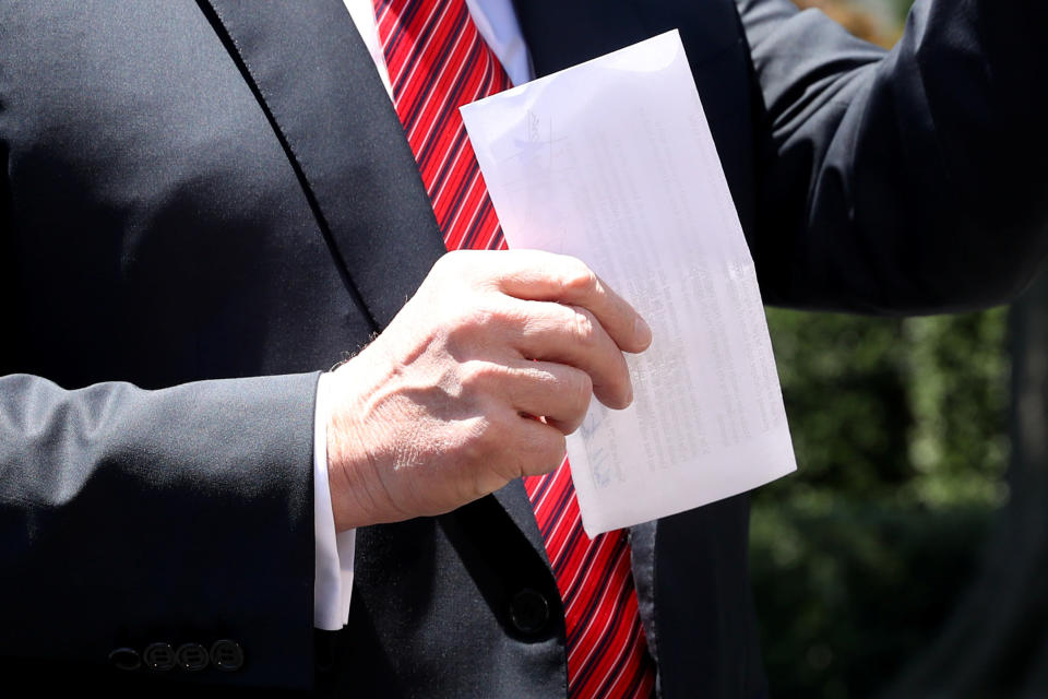 U.S. President Donald Trump holds up a copy of a deal with Mexico on immigration and trade as he speaks to the news media prior to departing for travel to Iowa from the White House in Washington, U.S., June 11, 2019. The document says the U.S.-Mexico migrant agreement reached last week includes a regional asylum plan and that Mexico agreed to examine its laws and potentially change them in order to implement the deal.  REUTERS/Leah Millis