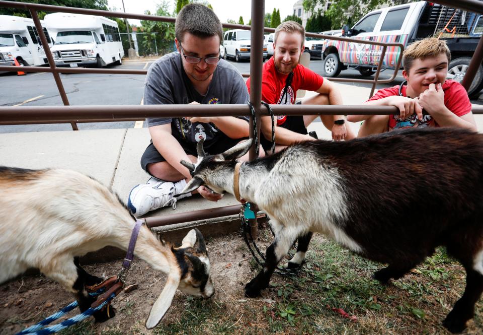 Arc of the Ozarks summer campers Ryan (left), 18, and Alex (right), 15, feed goats from Rafter C Rodeo Goats with Arc staff member Chris Winzen (center) during an activity day at the Timothy Grant Newport Activity Center on Thursday, July 28, 2022.