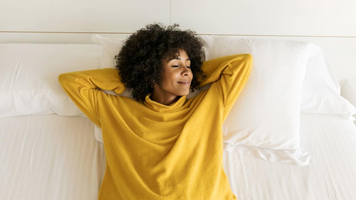 smiling woman with closed eyes lying on bed