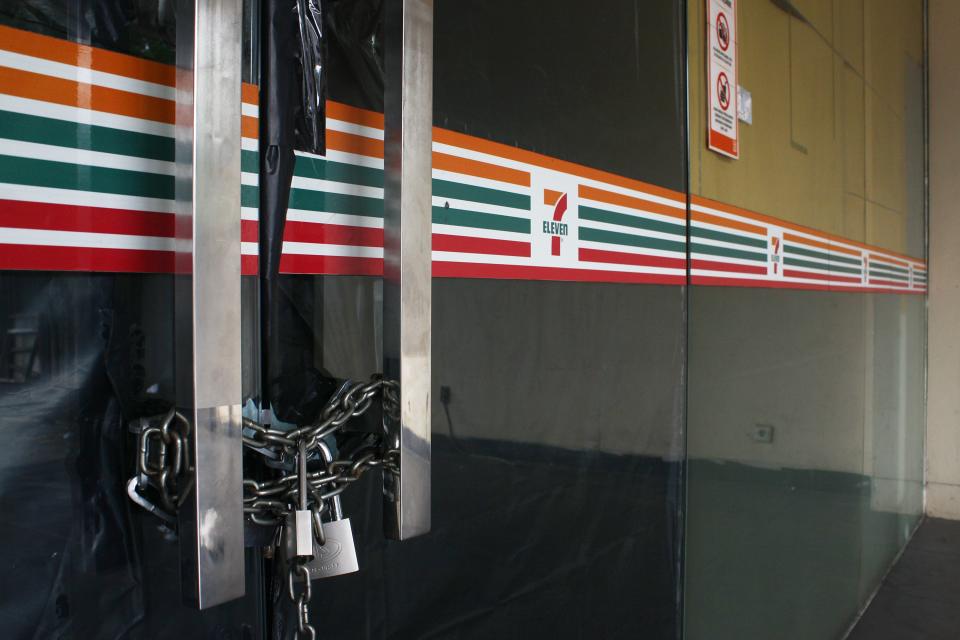 The front doors to a closed 7-Eleven store are seen with a chain and padlock securing them shut.