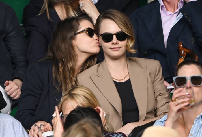 sitting in the stands, cara's girlfriend leans over to kiss cara's ear