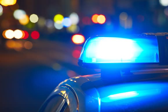 Top view of a police car traveling on a city street at night, which shows its flashing blue light.