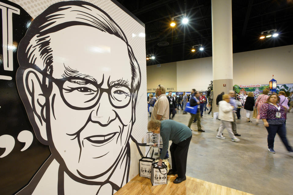 A Berkshire Hathaway shareholder arranges her shopping next to a large drawing of Chairman and CEO Warren Buffett, during a shareholders shopping event in Omaha, Neb., Friday, May 3, 2019, one day before Berkshire Hathaway's annual shareholders meeting. An estimated 40,000 people are expected in town for the event, where Chairman and CEO Warren Buffett and Vice Chairman Charlie Munger will preside over the meeting and spend hours answering questions. (AP Photo/Nati Harnik)