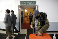 A Muslim makes a donation after an evening prayer called "tarawih" as others pass by during the first evening of the holy fasting month of Ramadan at Chicago's Muslim Community Center on Monday, April 12, 2021. (AP Photo/Shafkat Anowar)