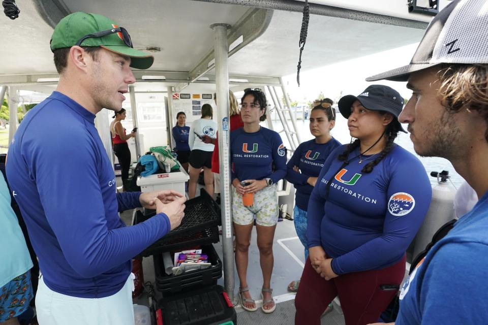 University of Miami Rosenstiel School of Marine, Atmospheric, and Earth Science senior research associate Dalton Hesley, left, explains the plan to divers, Friday, Aug. 4, 2023, on Paradise Reef near Key Biscayne, Fla. Scientists from the University of Miami Rosenstiel School of Marine, Atmospheric, and Earth Science established a new restoration research site there to identify and better understand the heat tolerance of certain coral species and genotypes during bleaching events. (AP Photo/Wilfredo Lee)