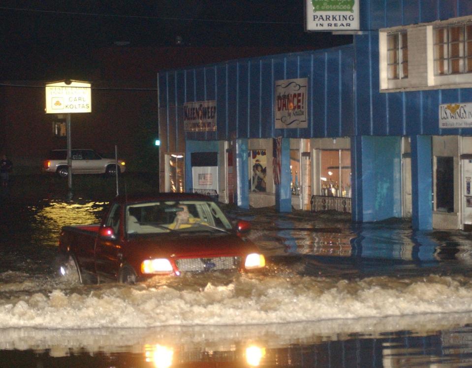 A car moves slowly though floodwater on state Route 59 in Stow just east of Darrow Road after heavy rain on Monday, July 21, 2003.