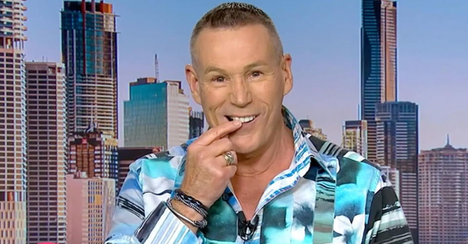 Studio 10 reporter Craig Bennett is wearing a blue and white patterned shirt and touches his tooth while looking at the camera