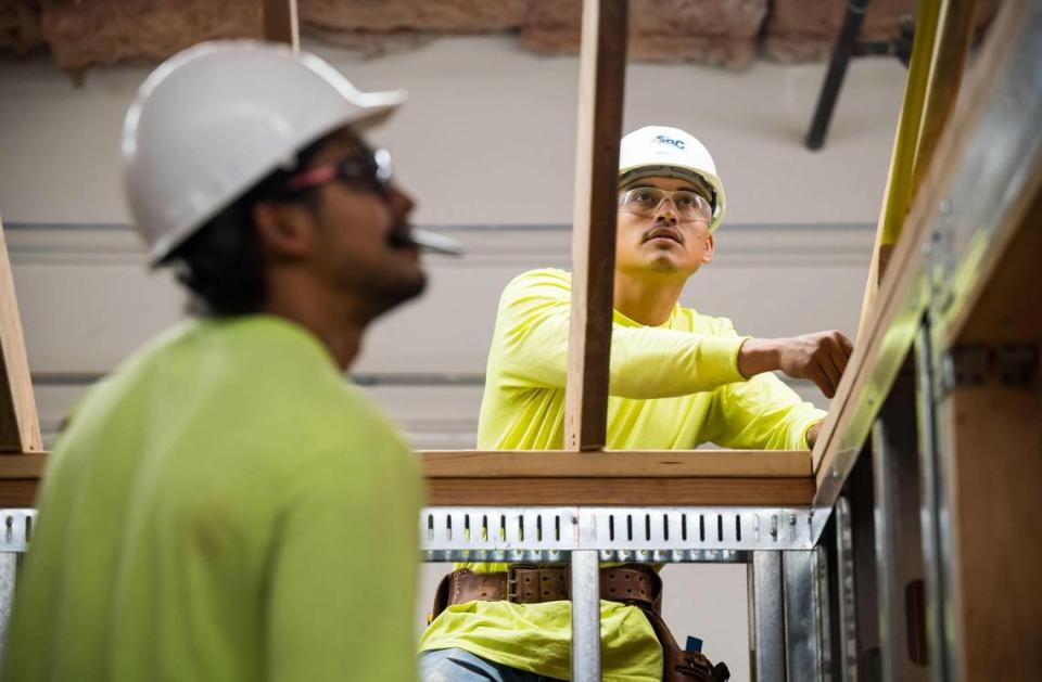 Angel Lopez, right, of Fresno, works with classmates to figure out their next steps while training as carpentry apprentices by building a structure indoors at the Associated Builders and Contractors Inc. training facility July 20, 2023, in North Highlands.