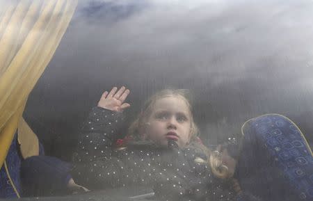 A girl, hoping to cross into Egypt with her family, looks out a bus window at the Rafah crossing between Egypt and the southern Gaza Strip December 21, 2014. REUTERS/Ibraheem Abu Mustafa