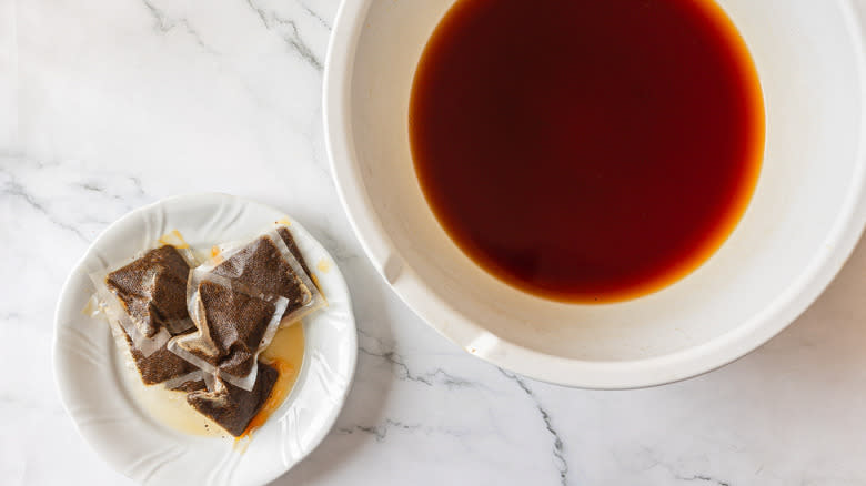 Tea in bowl beside plate with tea bags