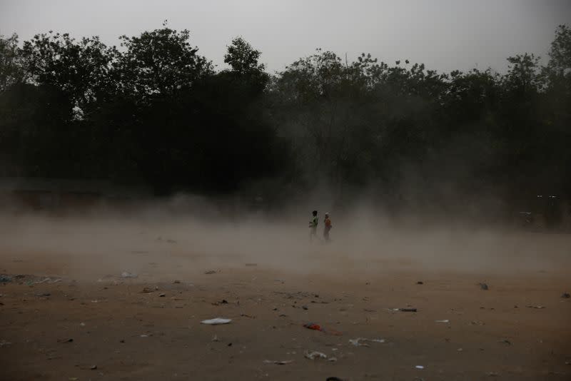 People walk during a dust storm in Ahmedabad