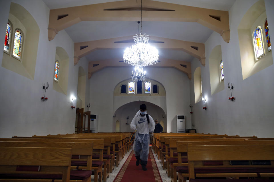 A municipal worker wearing protective gear sprays spray disinfectant as a precaution against the coronavirus, at a church in Beirut, Lebanon, Sunday, March 22, 2020. Lebanon has been taking strict measures to limit the spread of COVID-19 closing restaurants and nightclubs as well as schools and universities. (AP Photo/Bilal Hussein)