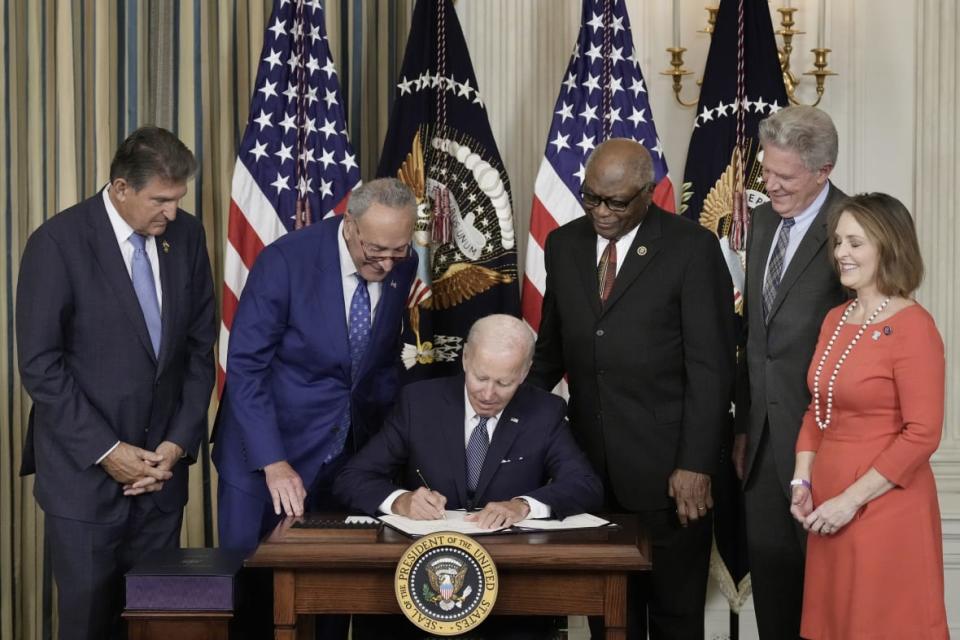 President Joe Biden, seated at the White House last August, signs the Inflation Reduction Act surrounded by (from left) Sen. Joe Manchin, Sen. Chuck Schumer, Rep. James Clyburn, Rep. Frank Pallone and Rep. Kathy Castor. This week, environmental and justice advocates say the funds the act provides toward implementing his climate policy are not enough. (Photo by Drew Angerer/Getty Images)