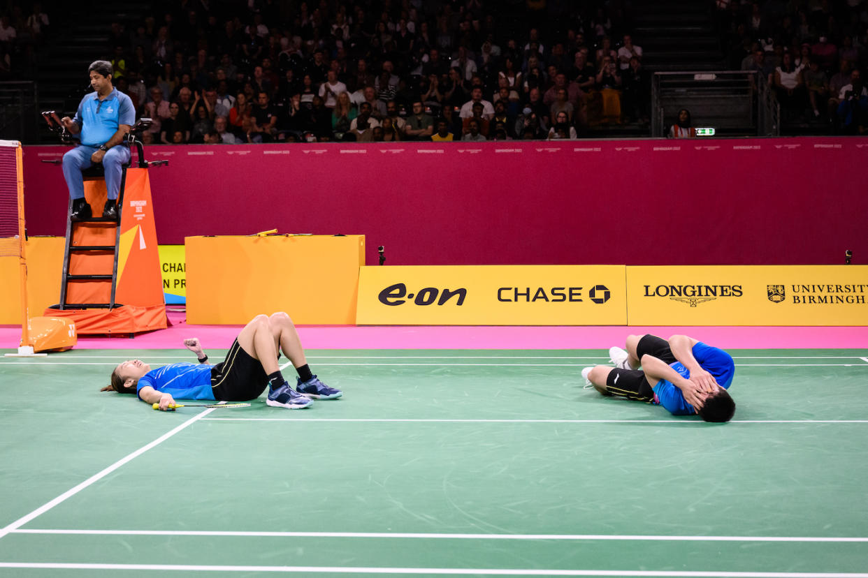 Singapore badminton pair Jessica Tan (left) and Terry Hee collapse in joy after winning the  mixed doubles gold at the 2022 Commonwealth Games. (PHOTO: Commonwealth Games Singapore/ Andy Chua)