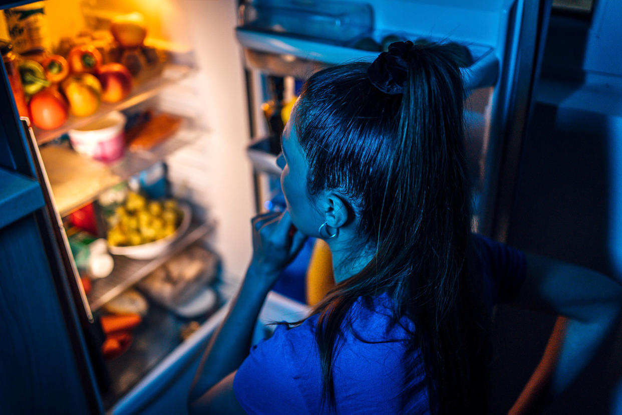 Young woman in front of the refrigerator at night Getty Images/LordHenriVoton