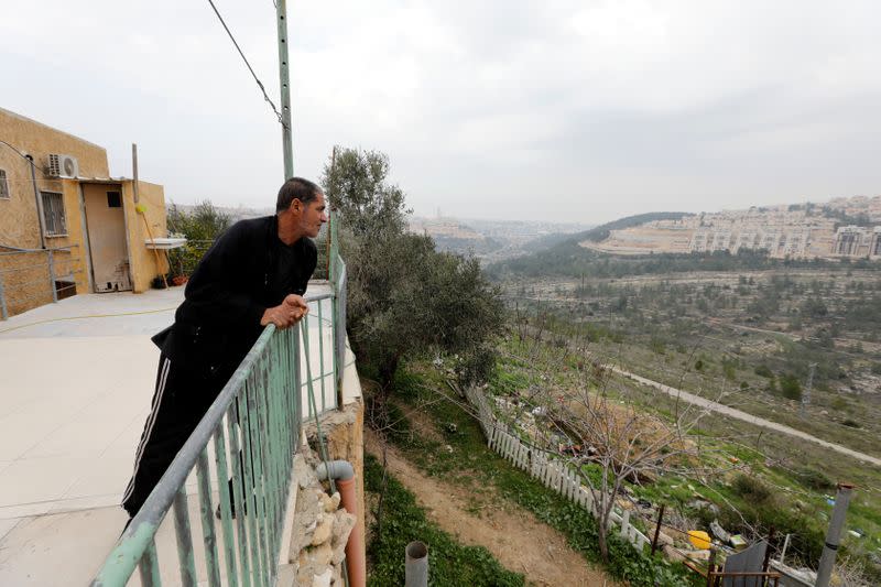 Palestinian man Omar Hajajla, who is cut off with his family from the rest of their village by the Israeli wall, looks out of his house at the Israeli settlement of Gilo, in Al-Walaja village near Bethlehem, in the Israeli-occupied West Bank