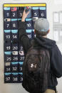 A ninth grader places his cellphone into a phone holder as he enters class at Delta High School, Friday, Feb. 23, 2024, in Delta, Utah. At the rural Utah school, there is a strict policy requiring students to check their phones at the door when entering every class. Each classroom has a cellphone storage unit that looks like an over-the-door shoe bag with three dozen smartphone-sized slots. (AP Photo/Rick Bowmer)