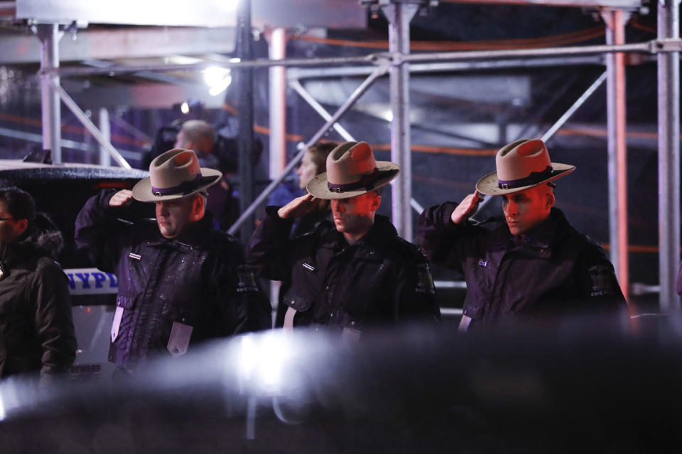 Officers salute a procession as the remains of slain Detective Brian Simonsen are removed from Jamaica Hospital Medical Center Tuesday, Feb. 12, 2019, in the Queens borough of New York. The NYPD detective and a NYPD sergeant were shot while responding to an armed robbery at a T-Mobile store in Queens. (AP Photo/Kevin Hagen)