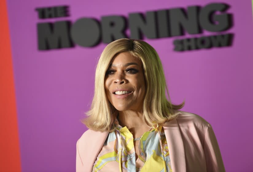 A woman with short blond hair posing against a purple background