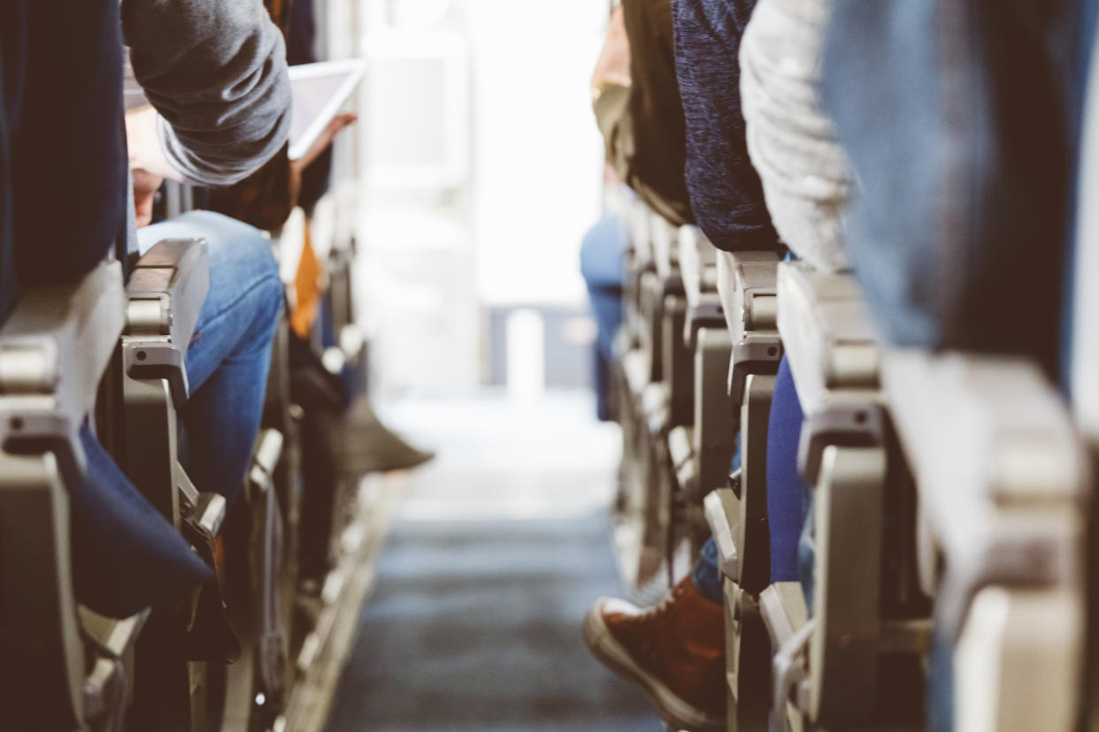 Rear view of commercial airliner cabin with passengers. Interior of airplane with people sitting on seats.